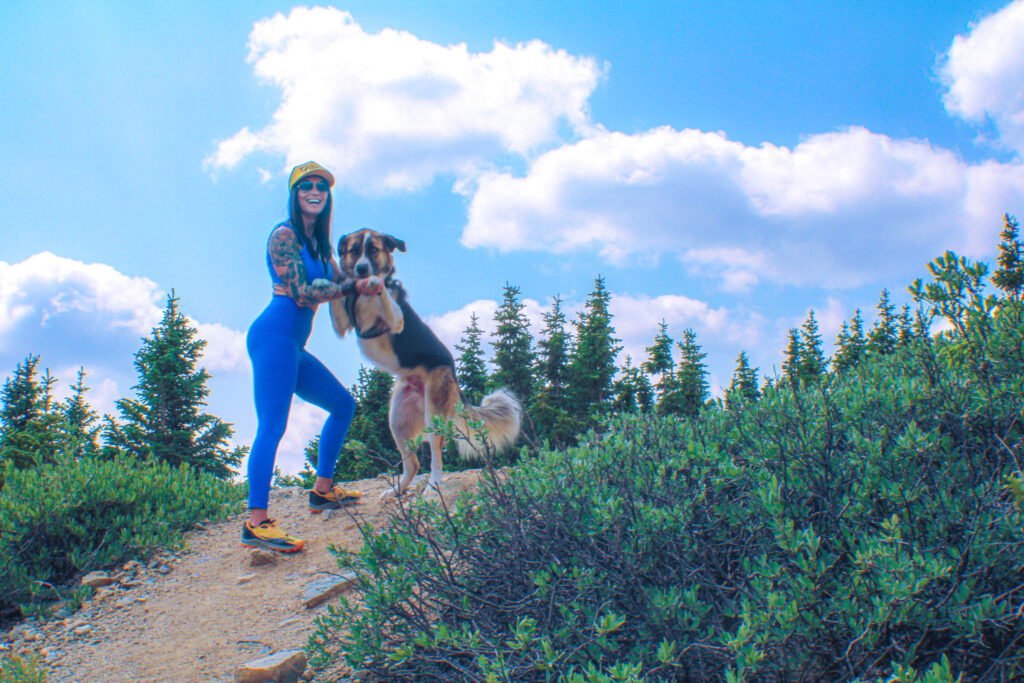 Kate Davis plays with her large dog, Moose, while hiking the Colorado Rockies.